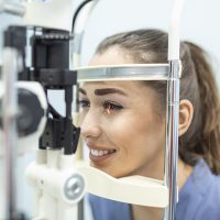 Eye doctor with female patient during an examination in modern clinic. Ophthalmologist is using special medical equipment for eye health